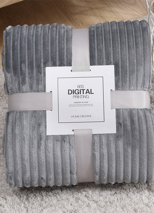 Folded gray textured blanket with a label on a light wooden floor.