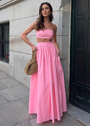 Woman in a pink outfit standing against a building wall.