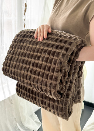 Person holding a folded brown textured blanket indoors