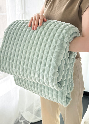 Person holding a light green textured blanket indoors