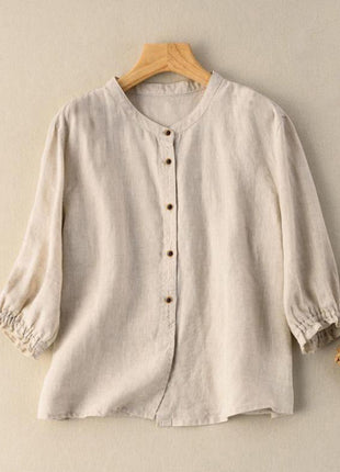 Beige blouse on a wooden hanger with a woven bag on a beige background