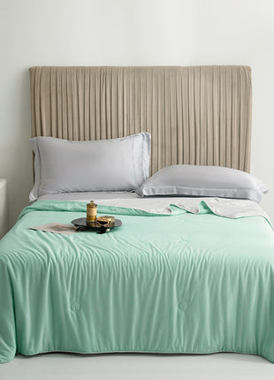 Bed with mint green comforter and beige headboard in a bedroom setting.