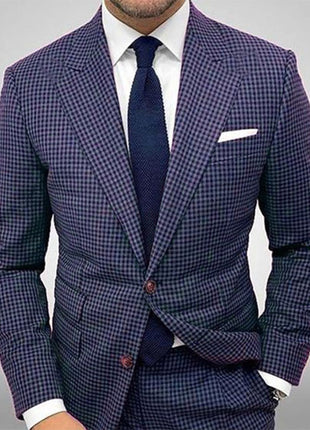 Man wearing a blue checkered suit with a white shirt and navy tie on a gray background