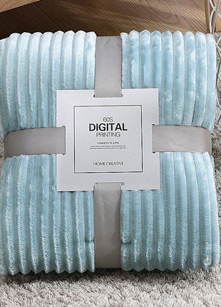 Light blue textured blanket with a brand label on a gray surface