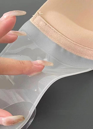 Beige bra with clear adhesive patch held by a hand on a dark background