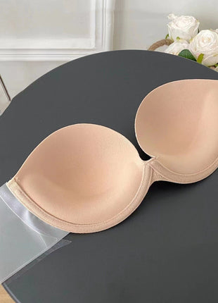 Beige strapless bra on a dark surface with white flowers in the background