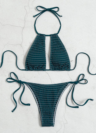 Teal bikini set with criss-cross straps on a light gray background