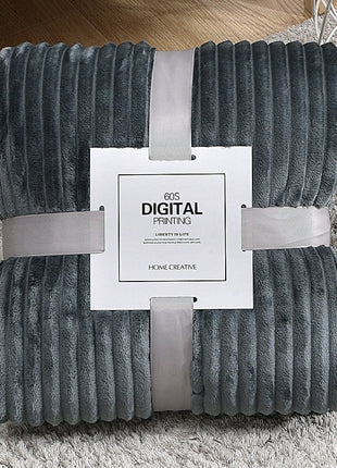 Folded gray textured blanket with a white label on a carpeted floor.