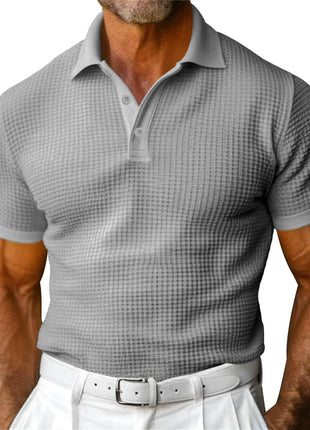 Man wearing a gray checkered polo shirt and white pants on a white background