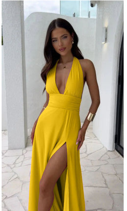 Woman wearing a yellow dress with a high slit in an outdoor setting