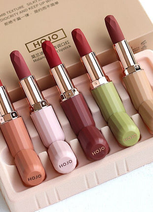 A set of five HOJO lipsticks in various colors displayed in a box with a velvet texture finish.
