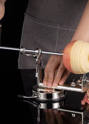Person using a apple peeler to peel an apple against a black background