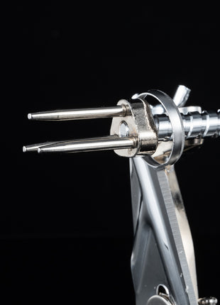 Close-up of a metallic tool with two prongs on a black background