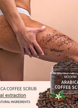 Person using Arabica Coffee Scrub on leg with product jar and coffee beans displayed.