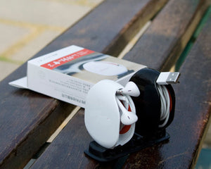 White and black electronic device on a wooden surface with a box in the background