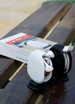 White and black electronic device on a wooden surface with a box in the background
