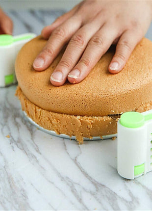 Person using a cake leveler to smooth layers of cake on a marble surface