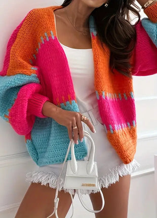Person wearing a colorful knit cardigan with a white handbag.