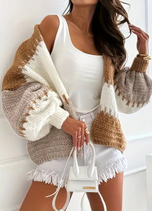 Woman wearing a brown and beige sweater with white accents, holding a white handbag.