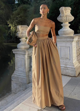 Woman in a beige strapless gown standing in an elegant outdoor setting with classical architecture.
