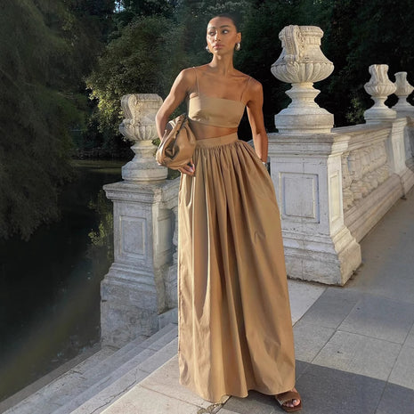 Woman in a beige strapless gown standing in an elegant outdoor setting with classical architecture.