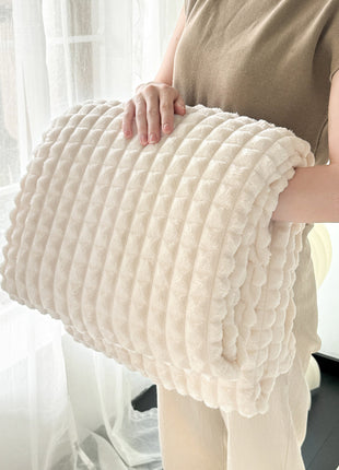 Person holding a textured beige pillow in a bright room with sheer curtains.