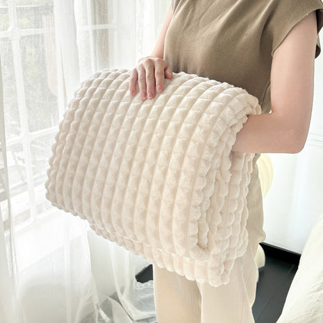 Person holding a textured beige pillow in a bright room with sheer curtains.