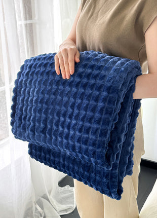 Person holding a blue textured blanket indoors