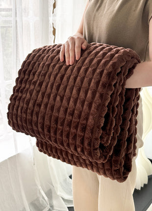 Person holding a brown textured blanket in front of a white curtain