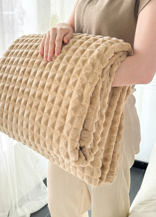 Person holding a beige textured blanket in a bright room