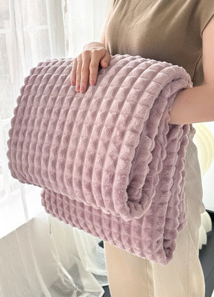 Person holding a pink textured blanket in front of a white curtain