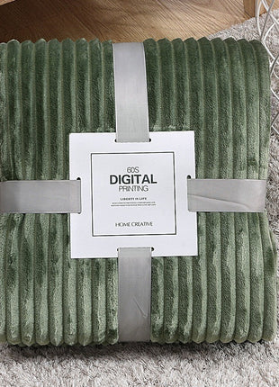 Green textured blanket with a white label on a gray surface