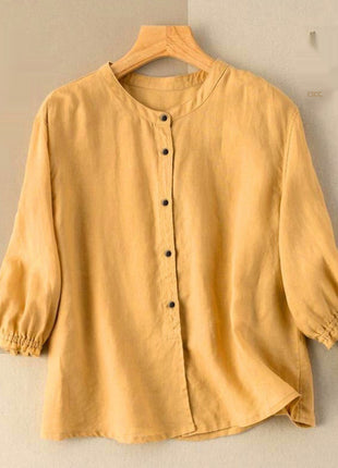 Yellow blouse on a hanger with a woven bag on a beige background