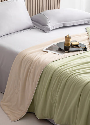 Bed with white bedding and a tray with a cup and book on a beige and green blanket.