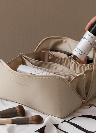 Beige cosmetic bag with makeup items on a white surface