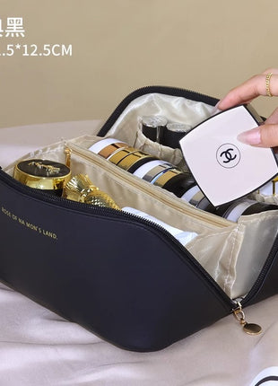 Black cosmetic bag with gold and white items on a beige surface