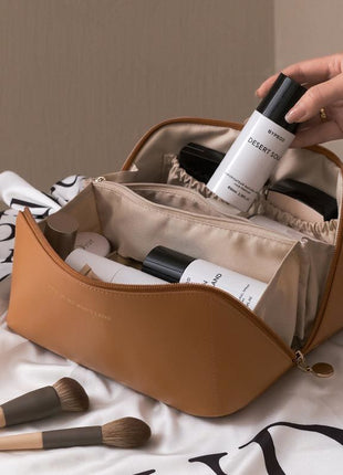 Brown cosmetic bag with skincare products and makeup brushes on a light background