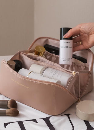 Cosmetic bag with skincare products and makeup brushes on a light surface