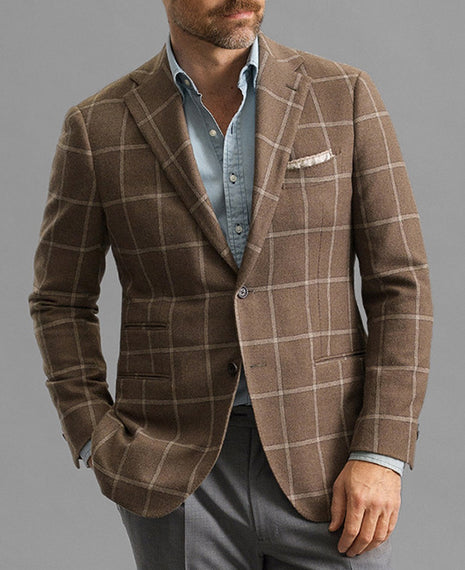 Man wearing a brown checkered blazer over a light blue shirt on a gray background