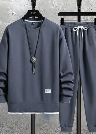 Gray sweatshirt and pants set on hangers against a gray wall.