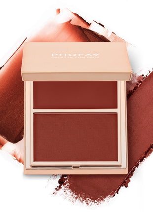 A selection of PHOFAY Duo Cream & Powder Blush products displayed on a pink surface, with the words 'JUST ENOUGH' visible in the image. The products come in golden-colored compact cases with brushes on one side and pink and red blush shades on the other.