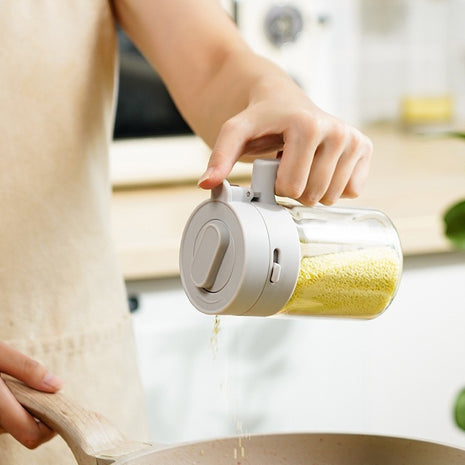 Person using a transparent container with a white lid to pour yellow powder into a bowl.
