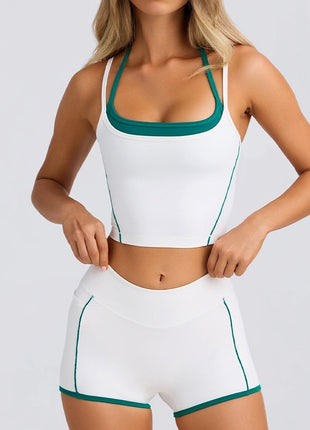Woman wearing a white sports bra and shorts with green trim on a light gray background