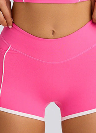 Pink athletic shorts with white trim on a plain background