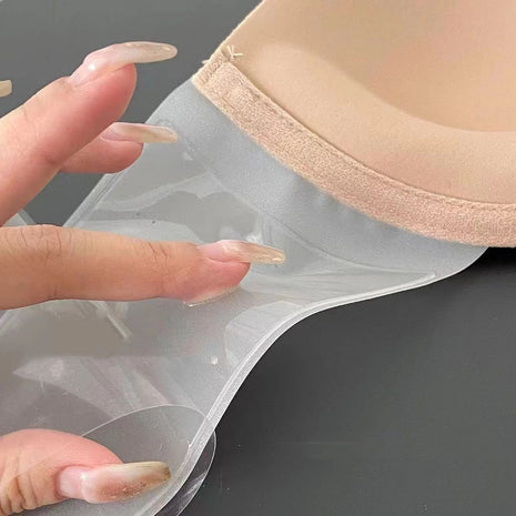 Beige bra with clear adhesive patch held by a hand on a dark background