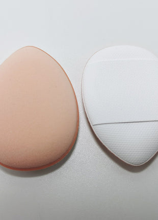 Two makeup sponges, one beige and one white, on a light gray background.