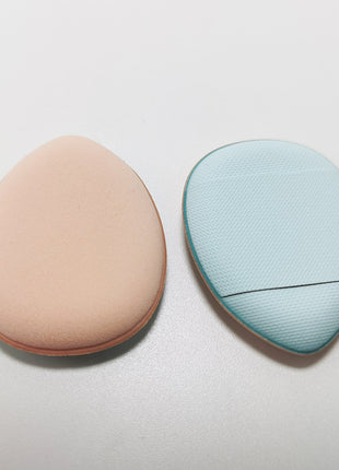 Two oval-shaped beauty tools, one beige and one light blue, on a light gray background.