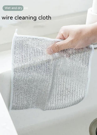 Wire cleaning cloth held by a hand over a sink