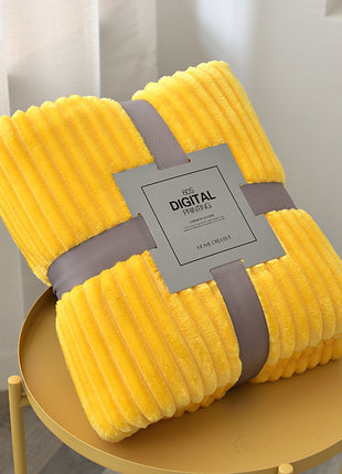 Yellow plush blanket with a brand label on a round gold table.