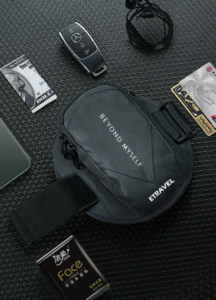 Black waist bag with 'Etravel' branding on a textured black surface with various items around it.